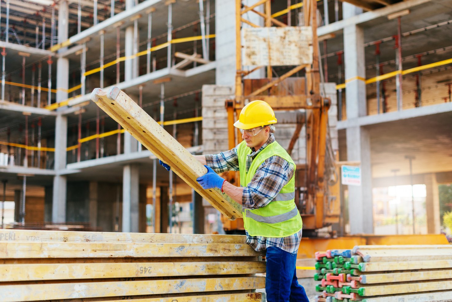 Manual construction worker working on construction platform, transferring construction material