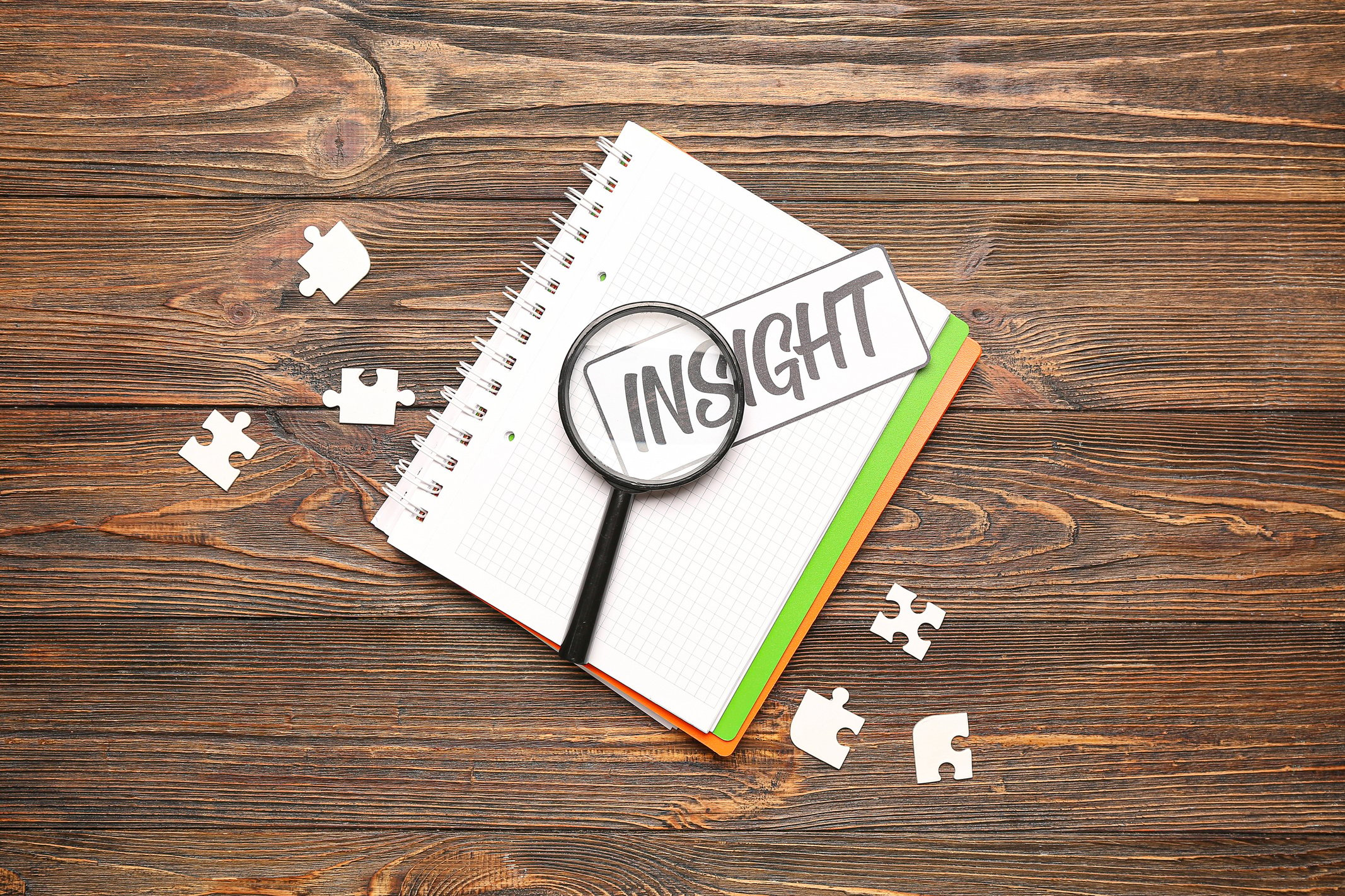 Notebook with Word INSIGHT, Magnifier and Puzzle Pieces on Wooden Background